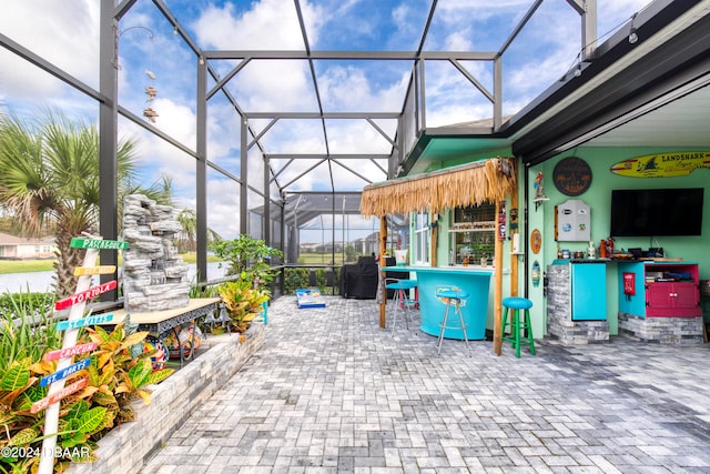 view of patio featuring an outdoor bar and glass enclosure