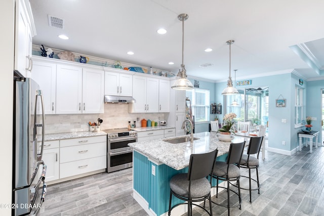 kitchen with stainless steel appliances, sink, an island with sink, light hardwood / wood-style floors, and white cabinets