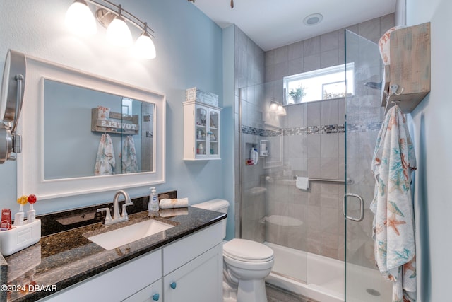 bathroom with a shower with shower door, vanity, and toilet