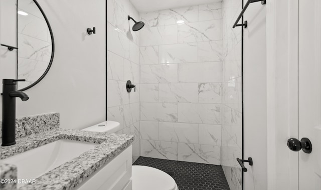 bathroom featuring vanity, toilet, and a tile shower