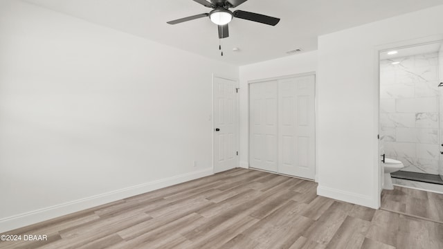 unfurnished bedroom featuring ceiling fan, connected bathroom, a closet, and light wood-type flooring