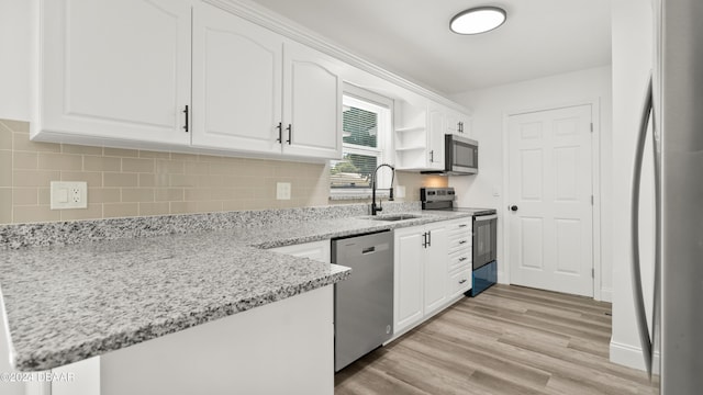 1801 James St, South Daytona, FL 32119 - kitchen featuring appliances with stainless steel finishes, a sink, white cabinets, light wood finished floors, and light stone countertops