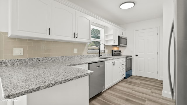 kitchen featuring stainless steel appliances, sink, light stone countertops, white cabinetry, and light hardwood / wood-style flooring