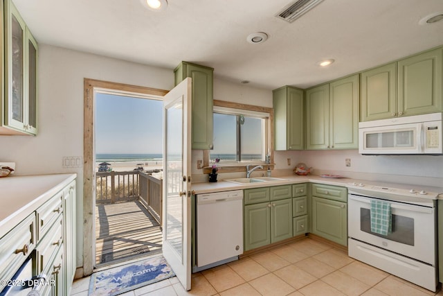 kitchen featuring green cabinets, white appliances, plenty of natural light, and a sink