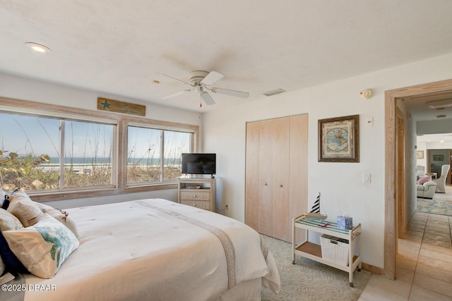 bedroom featuring light tile patterned flooring, visible vents, baseboards, a ceiling fan, and a closet