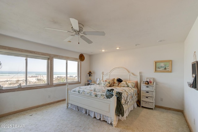 bedroom with a water view, ceiling fan, baseboards, and light colored carpet