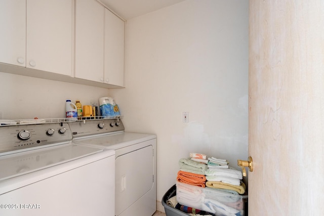 clothes washing area featuring independent washer and dryer and cabinet space