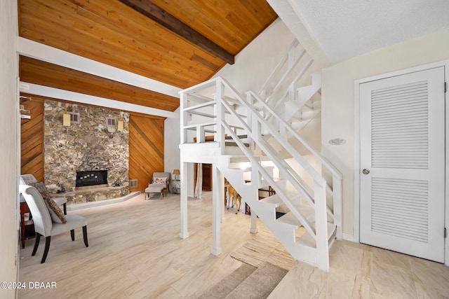 stairway with beam ceiling, wooden walls, wood ceiling, and a fireplace