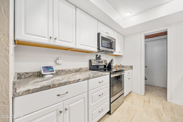 kitchen featuring white cabinets, appliances with stainless steel finishes, and light stone counters