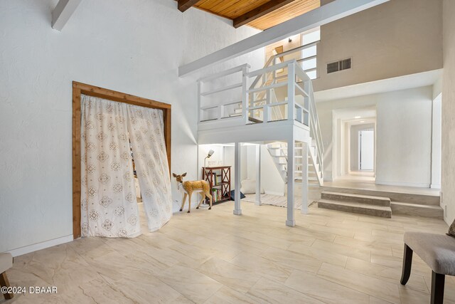 interior space with plenty of natural light, a towering ceiling, wooden ceiling, and beam ceiling