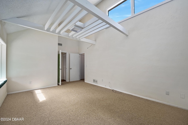 spare room featuring a high ceiling, carpet, a textured ceiling, and beam ceiling