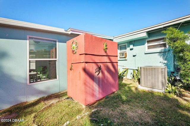 view of side of property with a yard and central AC