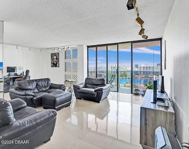 tiled living room with a textured ceiling, floor to ceiling windows, a water view, and track lighting