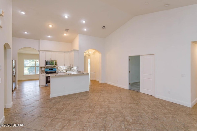 kitchen featuring white cabinets, decorative backsplash, stainless steel appliances, and high vaulted ceiling