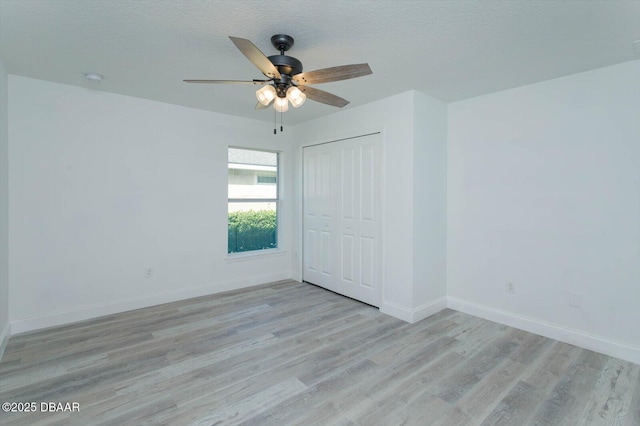 spare room featuring ceiling fan, light wood-type flooring, and a textured ceiling