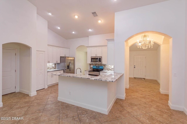 kitchen featuring light stone countertops, backsplash, kitchen peninsula, white cabinets, and appliances with stainless steel finishes