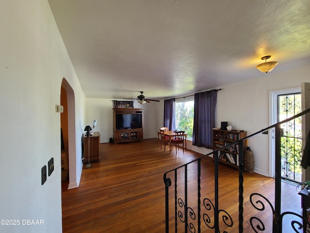 living room with hardwood / wood-style flooring, baseboards, arched walkways, and ceiling fan