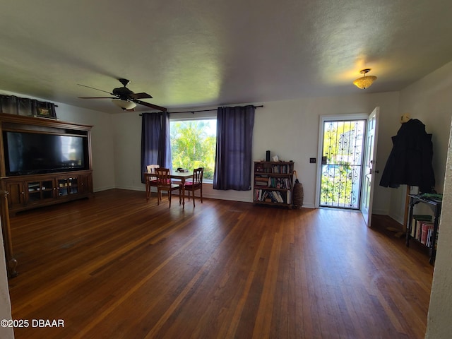 living area with a wealth of natural light, dark wood finished floors, and ceiling fan