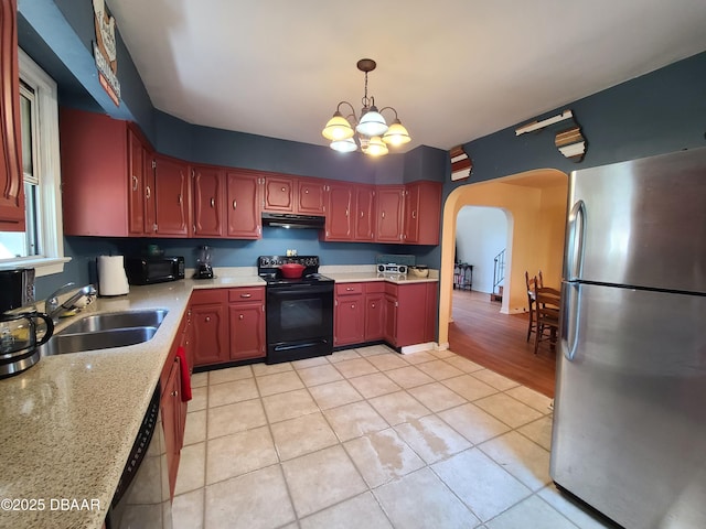 kitchen with under cabinet range hood, a chandelier, arched walkways, black appliances, and a sink