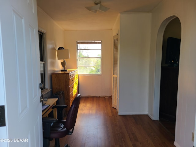 office area with arched walkways and dark wood-type flooring