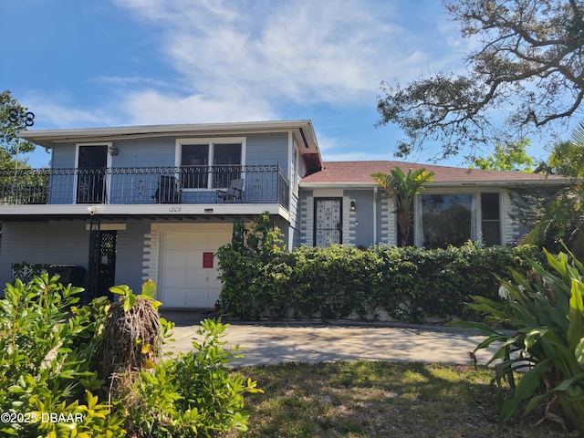 view of front of property featuring an attached garage, concrete driveway, and a balcony