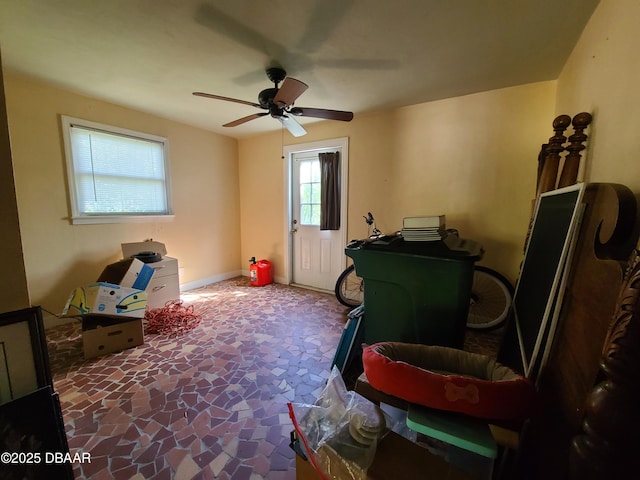 interior space featuring stone finish floor, baseboards, and ceiling fan