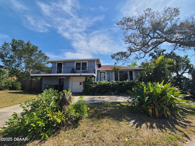 view of front of property featuring a front lawn, driveway, an attached garage, and a balcony