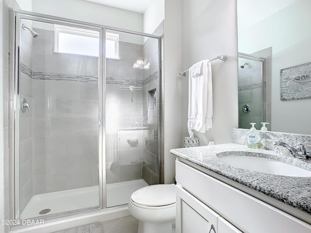 bathroom with tile patterned floors, vanity, an enclosed shower, and toilet