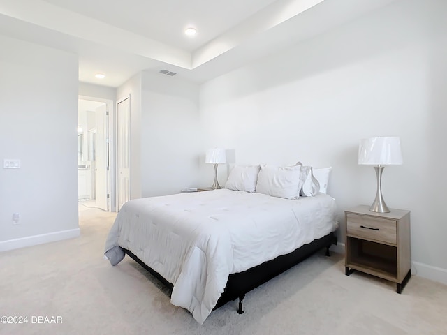 bedroom featuring light carpet, ensuite bathroom, and a closet