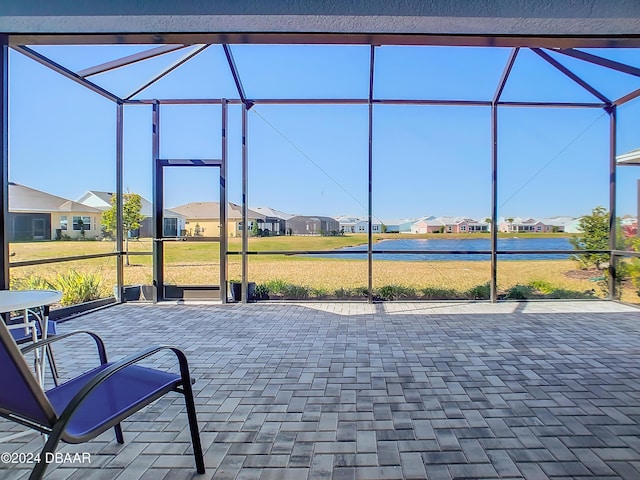 view of patio featuring a lanai and a water view