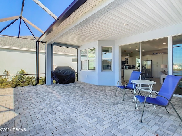 view of patio featuring glass enclosure and a grill