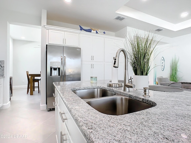 kitchen featuring stainless steel fridge with ice dispenser, sink, white cabinets, and light stone countertops