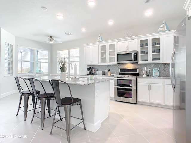 kitchen with sink, white cabinets, stainless steel appliances, and a center island with sink