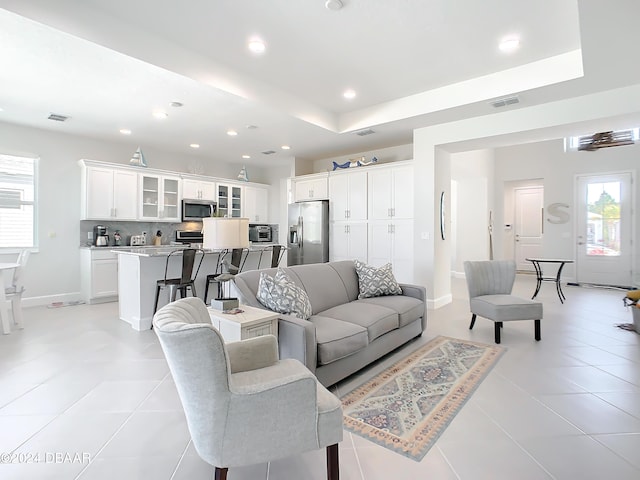 living room featuring light tile patterned floors and a tray ceiling