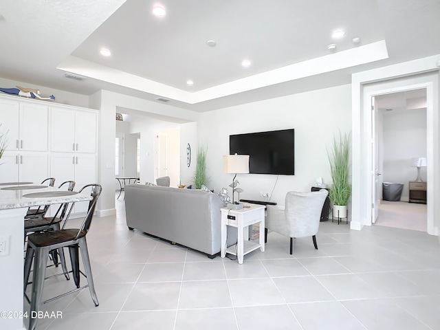 living room with a tray ceiling and light tile patterned flooring