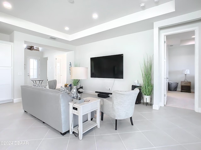 living room featuring a raised ceiling and light tile patterned flooring