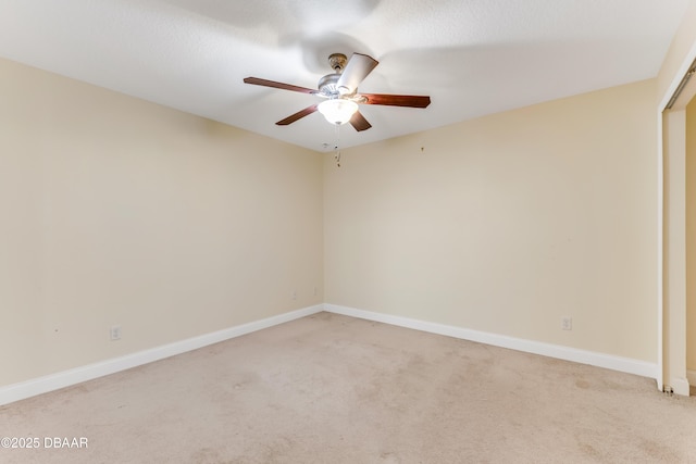 spare room with light colored carpet, baseboards, and ceiling fan