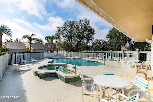 community pool with a patio area, a hot tub, and fence