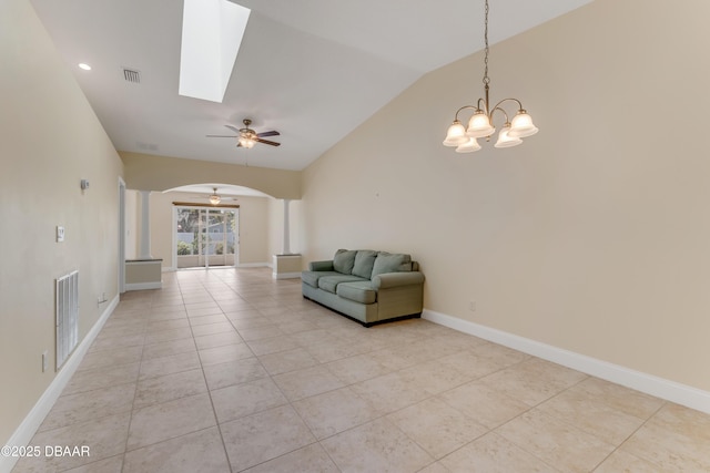 unfurnished room with visible vents, lofted ceiling with skylight, a ceiling fan, arched walkways, and baseboards