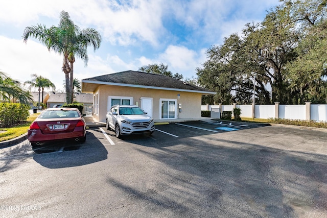 view of front of home with stucco siding, uncovered parking, and fence