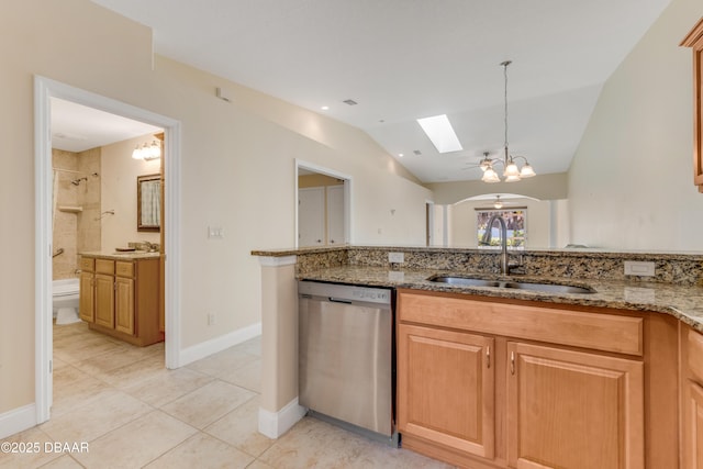 kitchen featuring a sink, light stone countertops, stainless steel dishwasher, and vaulted ceiling with skylight