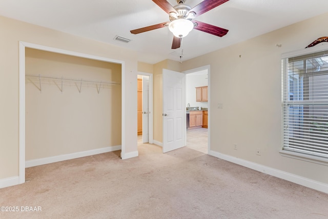 unfurnished bedroom featuring visible vents, baseboards, light colored carpet, multiple windows, and a closet