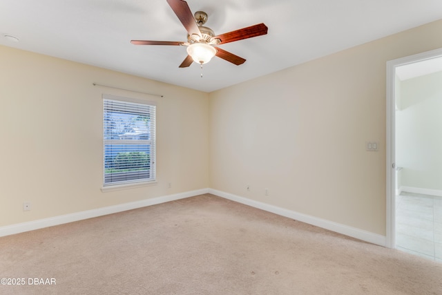 spare room featuring light colored carpet, baseboards, and ceiling fan