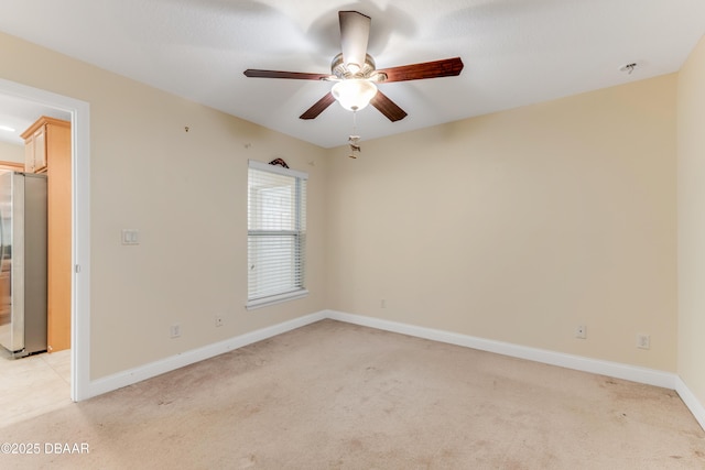 spare room featuring light colored carpet, baseboards, and ceiling fan