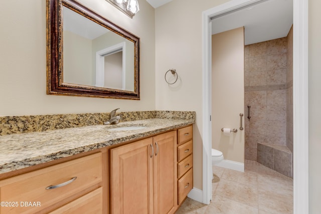 bathroom with baseboards, toilet, tiled shower, tile patterned floors, and vanity