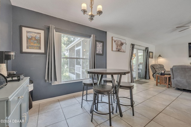 tiled dining room featuring plenty of natural light, ceiling fan with notable chandelier, and vaulted ceiling