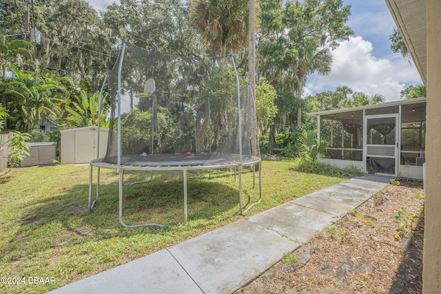 view of yard featuring a sunroom, a storage shed, and a trampoline