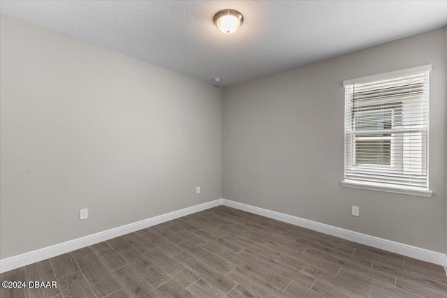 empty room featuring wood-type flooring and a textured ceiling