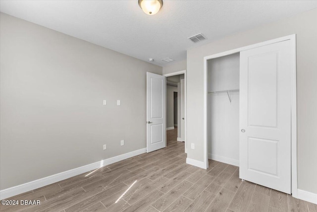 unfurnished bedroom with a closet, a textured ceiling, and light hardwood / wood-style floors