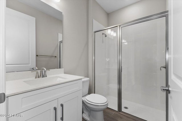 bathroom featuring toilet, vanity, an enclosed shower, and hardwood / wood-style flooring